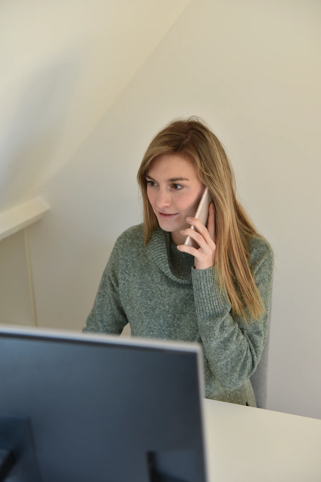 A woman speaking on a phone at her desk